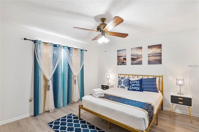 bedroom with baseboards, a ceiling fan, wood finished floors, and a textured ceiling
