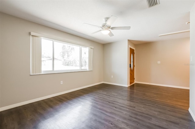 empty room with dark wood-style flooring, visible vents, a ceiling fan, and baseboards