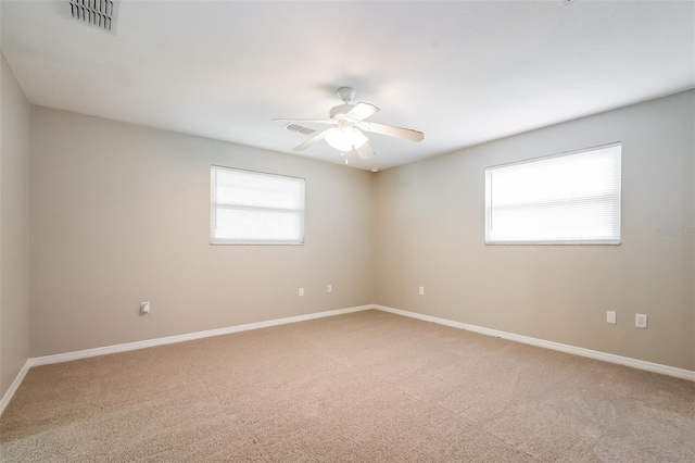 unfurnished room featuring a ceiling fan, visible vents, light carpet, and baseboards