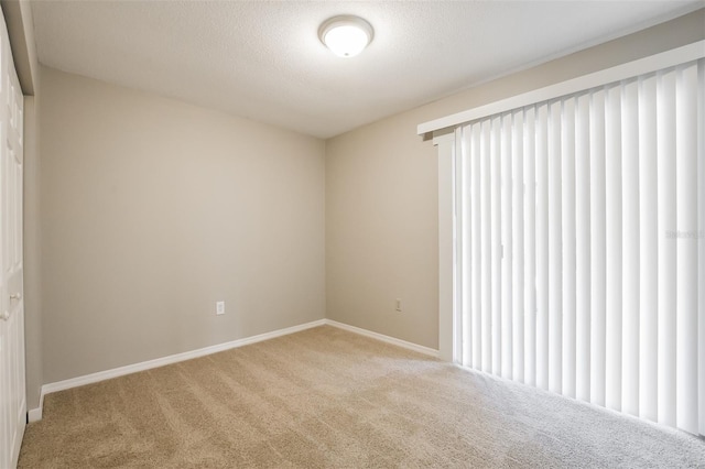 carpeted empty room featuring a textured ceiling and baseboards