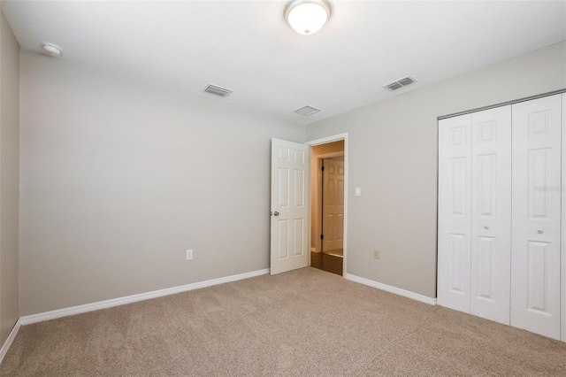 unfurnished bedroom with baseboards, visible vents, a closet, and carpet