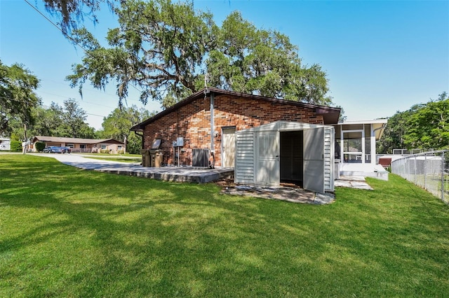 back of house featuring a lawn, fence, and brick siding