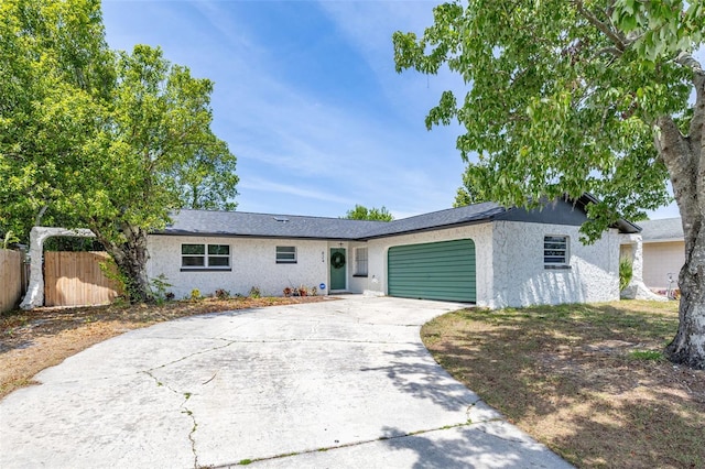single story home with fence, concrete driveway, stucco siding, and an attached garage