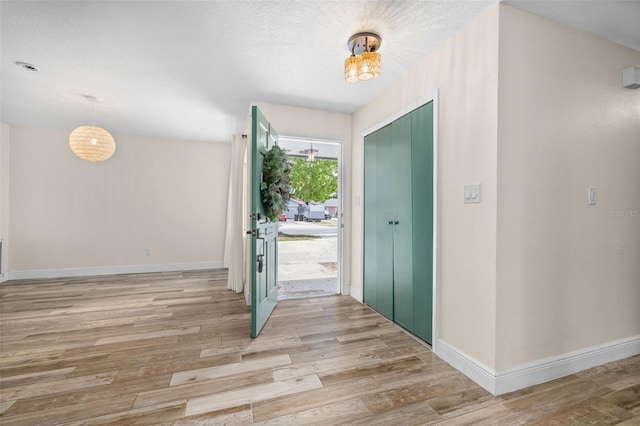 entryway featuring a chandelier, light wood-type flooring, and baseboards