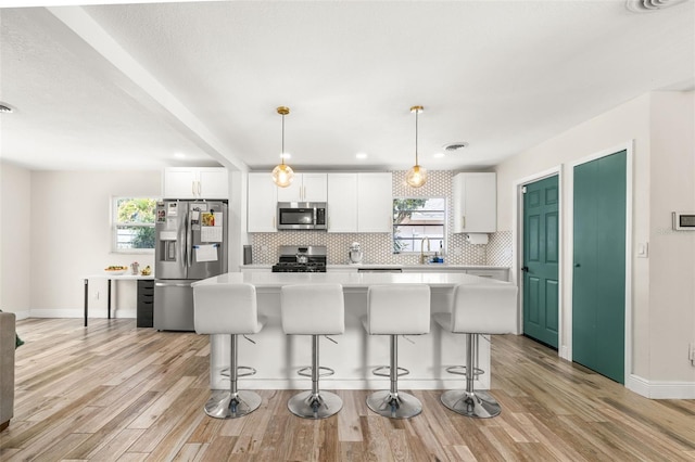 kitchen with light countertops, a kitchen island, stainless steel appliances, and a healthy amount of sunlight