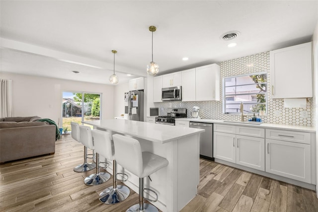 kitchen with a breakfast bar area, stainless steel appliances, a sink, visible vents, and open floor plan