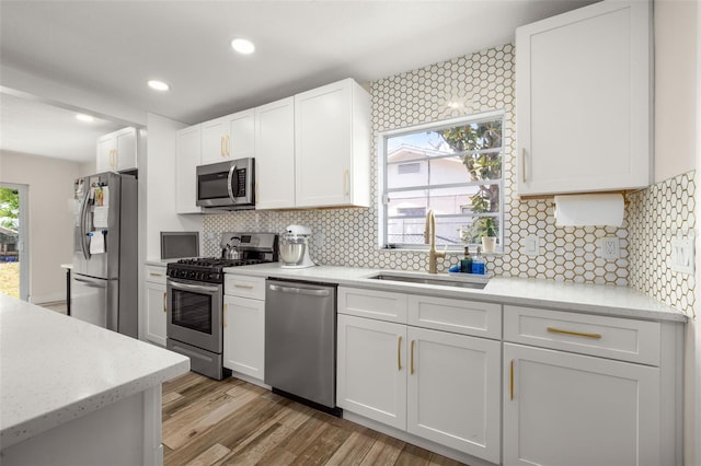 kitchen with backsplash, a sink, white cabinets, and appliances with stainless steel finishes
