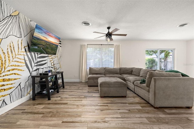 living room featuring visible vents, ceiling fan, light wood-style flooring, and baseboards