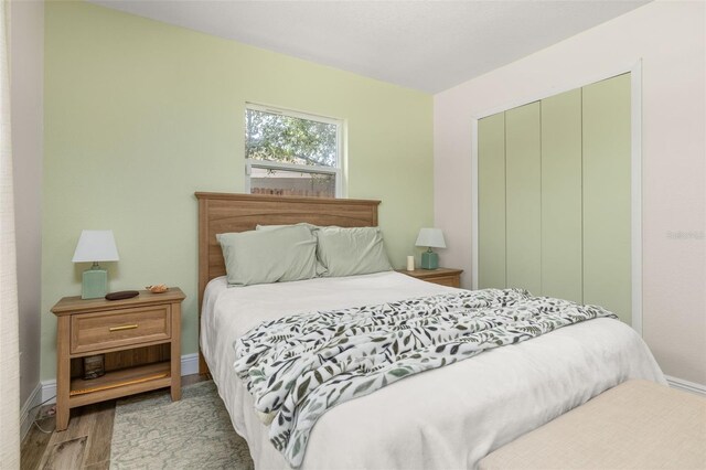 bedroom featuring baseboards, wood finished floors, and a closet