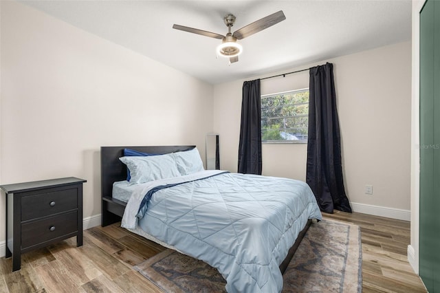 bedroom featuring baseboards, wood finished floors, and ceiling fan
