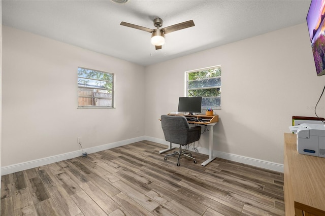 office featuring wood finished floors, a healthy amount of sunlight, and a ceiling fan