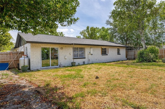 back of property featuring a lawn, stucco siding, and a fenced backyard