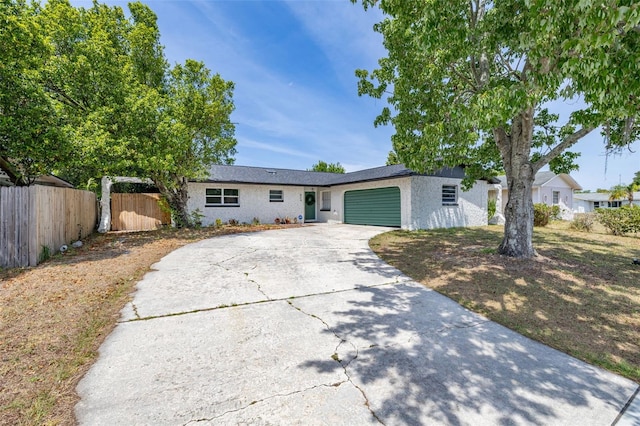ranch-style house featuring driveway, fence, and an attached garage