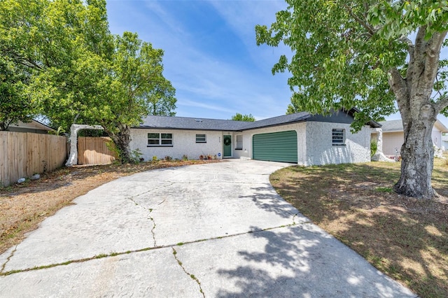 ranch-style house with fence, stucco siding, driveway, and an attached garage