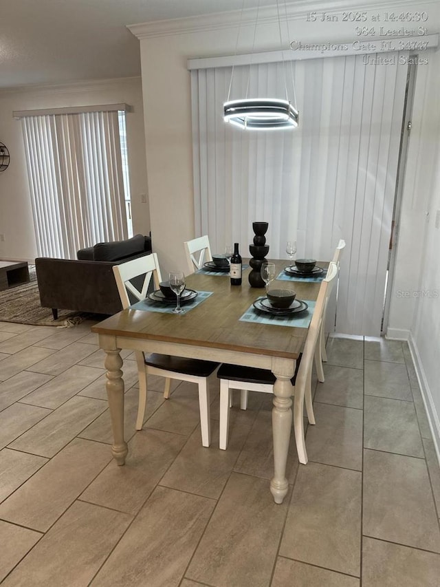 dining area featuring ornamental molding, light tile patterned floors, and baseboards