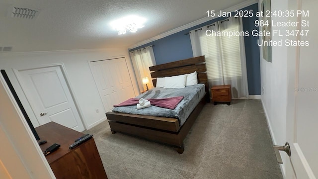 carpeted bedroom with ornamental molding, a textured ceiling, visible vents, and baseboards