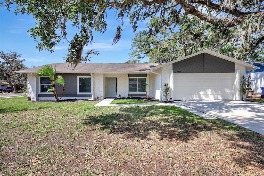 single story home featuring a garage, stucco siding, a front yard, and concrete driveway