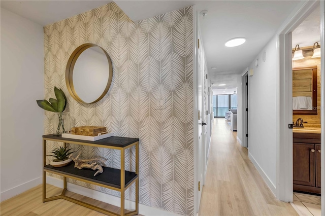 4139 S Atlantic Ave Unit B707, New Smyrna Beach, FL 32169 - corridor featuring baseboards, a sink, an accent wall, and wallpapered walls