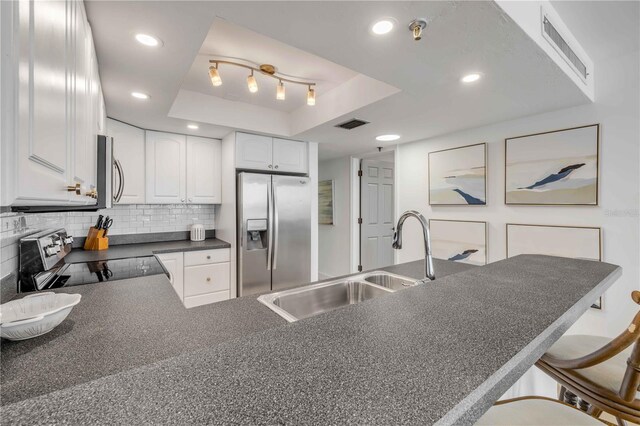 4139 S Atlantic Ave Unit B707, New Smyrna Beach, FL 32169 - kitchen featuring dark countertops, appliances with stainless steel finishes, a sink, a tray ceiling, and visible vents