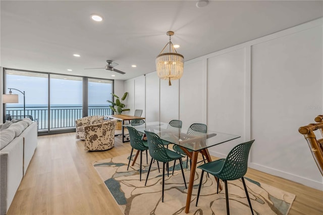 4139 S Atlantic Ave Unit B707, New Smyrna Beach, FL 32169 - dining area featuring a wall of windows, a decorative wall, light wood-style flooring, ceiling fan with notable chandelier, and recessed lighting