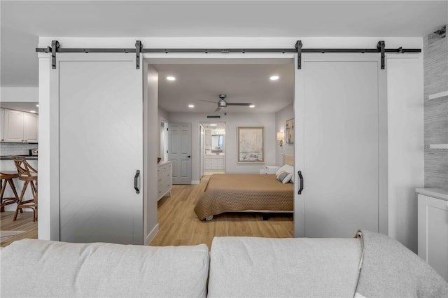4139 S Atlantic Ave Unit B707, New Smyrna Beach, FL 32169 - bedroom with light wood-style floors, a barn door, connected bathroom, and recessed lighting