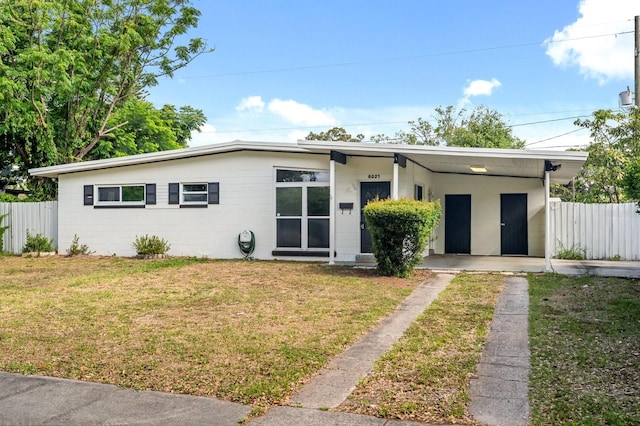 6021 Navajo Way, Orlando, FL 32807 - mid-century modern home with fence, a front lawn, driveway, and concrete block siding