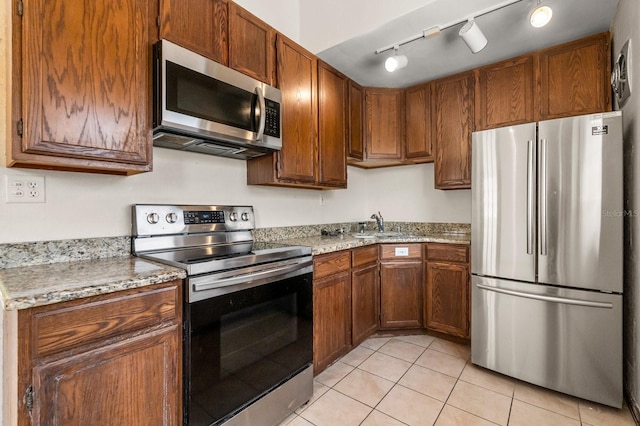 6021 Navajo Way, Orlando, FL 32807 - kitchen featuring stainless steel appliances, a sink, light tile patterned flooring, and brown cabinets