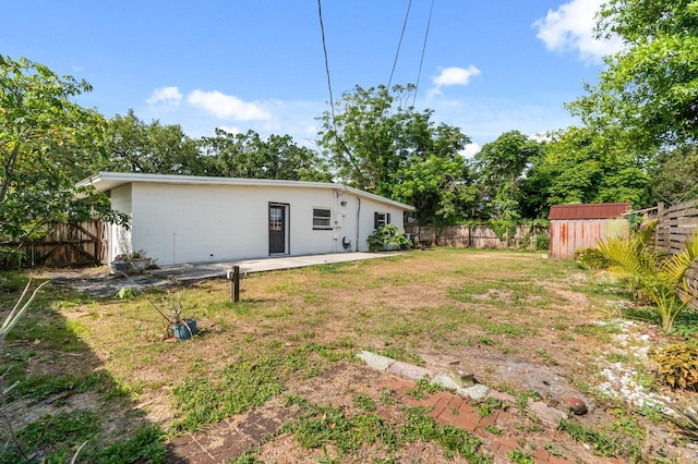 6021 Navajo Way, Orlando, FL 32807 - back of property with a patio, a storage unit, fence, and a lawn