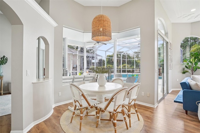 336 Plantation Club Dr, Debary, FL 32713 - dining space with wood-type flooring, baseboards, a sunroom, a high ceiling, and arched walkways