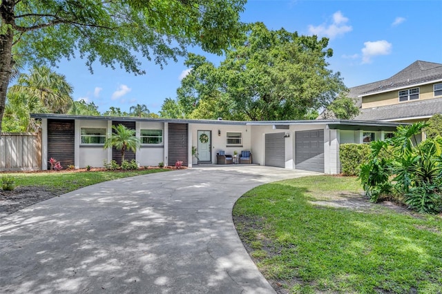 view of front of property with fence, a front yard, concrete driveway, and an attached garage