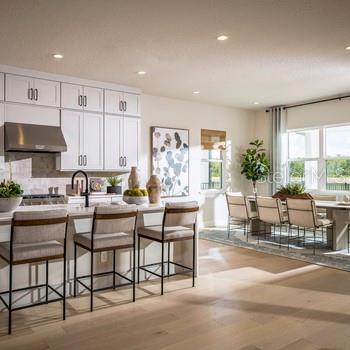 9429 Golden Laurel Ln, Orlando, FL 32827 - kitchen with under cabinet range hood, backsplash, white cabinets, recessed lighting, and a kitchen bar