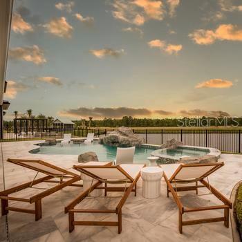 9429 Golden Laurel Ln, Orlando, FL 32827 - pool at dusk featuring a patio and a pool with connected hot tub