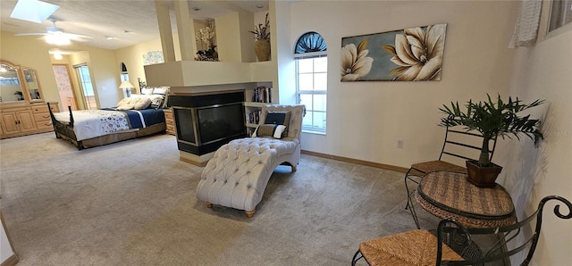62 Barkley Ln, Palm Coast, FL 32137 - bedroom with light carpet, a skylight, a multi sided fireplace, and baseboards