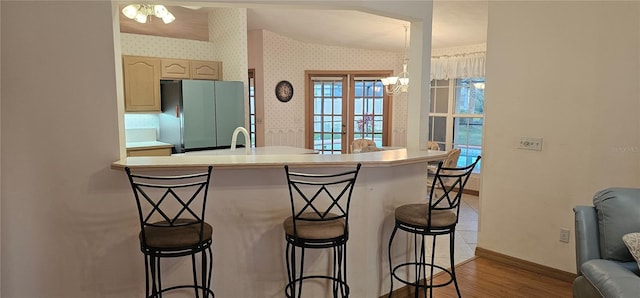 62 Barkley Ln, Palm Coast, FL 32137 - kitchen with freestanding refrigerator, wallpapered walls, a breakfast bar area, wood finished floors, and baseboards
