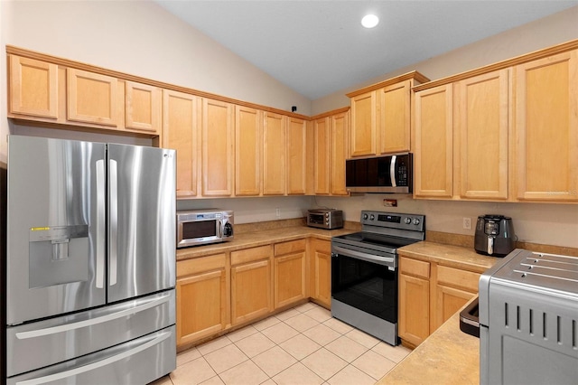 kitchen with appliances with stainless steel finishes, light brown cabinets, light countertops, and vaulted ceiling
