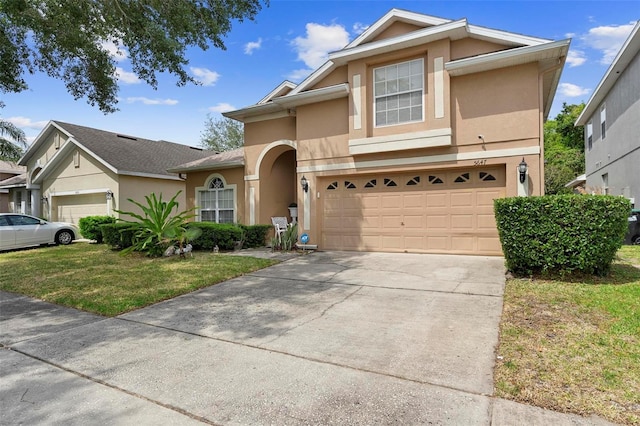 view of front of house with an attached garage, concrete driveway, a front yard, and stucco siding