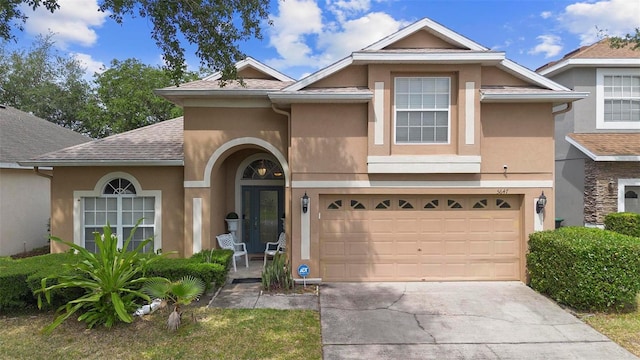 view of front of property featuring driveway, a shingled roof, stucco siding, and a garage