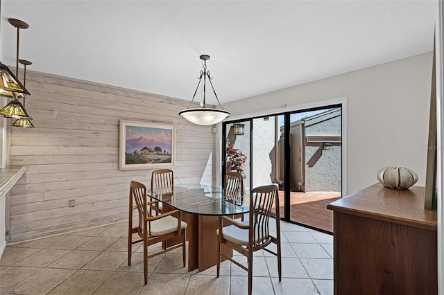 dining space featuring light tile patterned flooring and wooden walls