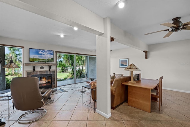 living room with ceiling fan, baseboards, a tiled fireplace, and plenty of natural light