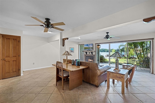 living room with a glass covered fireplace, a healthy amount of sunlight, and ceiling fan