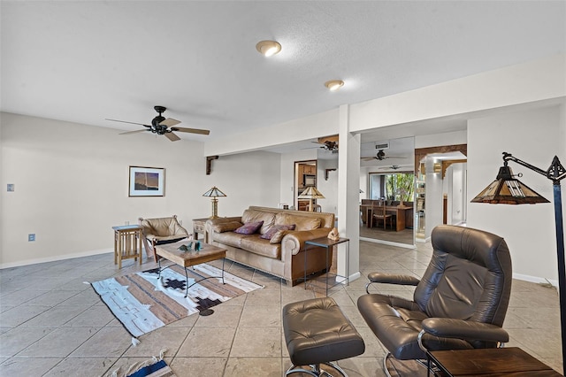 living area with light tile patterned floors, a ceiling fan, and baseboards
