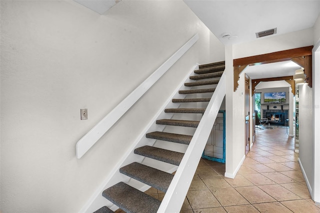 stairs with visible vents, tile patterned flooring, and baseboards