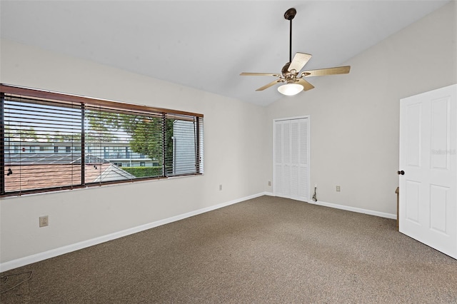 carpeted empty room featuring baseboards, ceiling fan, and vaulted ceiling