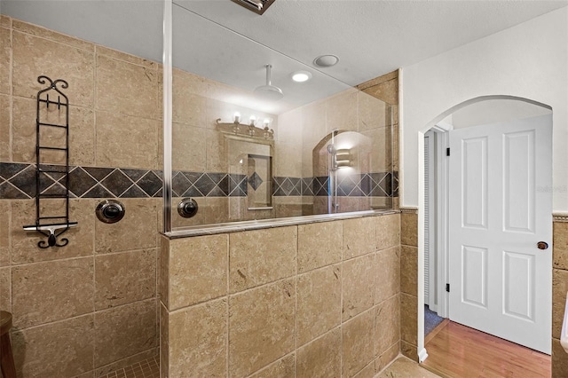 bathroom with tile walls, a walk in shower, wainscoting, and wood finished floors