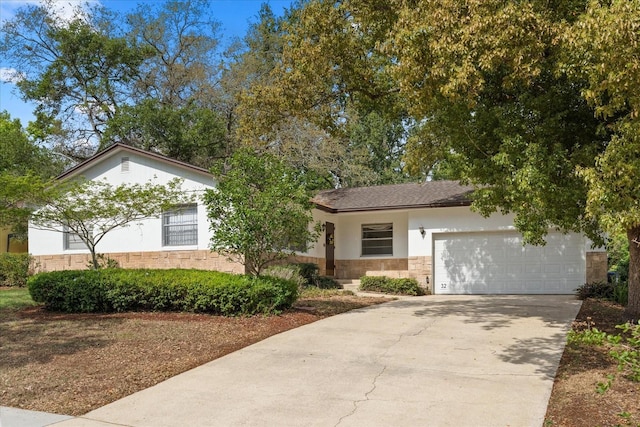 ranch-style house with concrete driveway, stucco siding, stone siding, and a garage