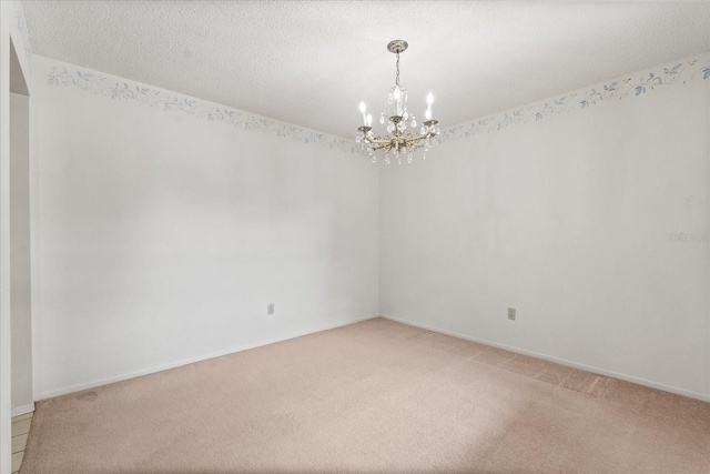 empty room with light colored carpet, an inviting chandelier, and baseboards