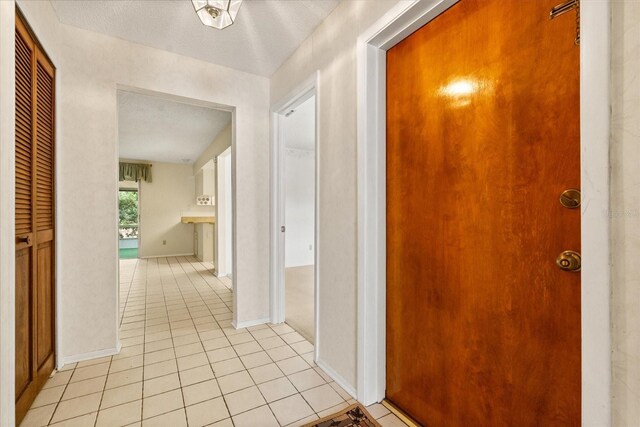corridor featuring baseboards and light tile patterned floors