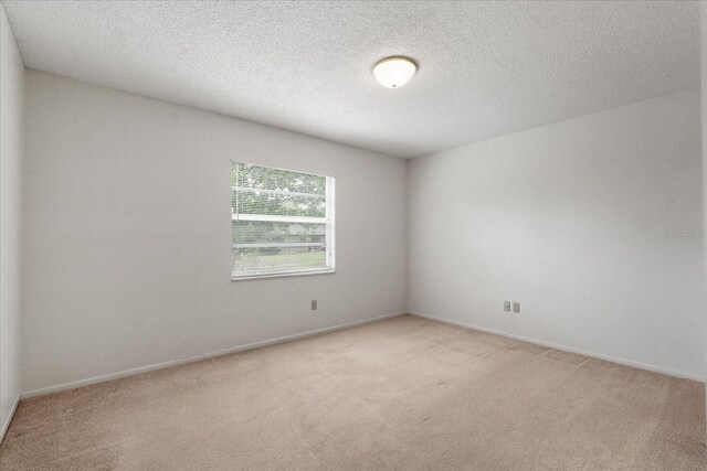 carpeted empty room with baseboards and a textured ceiling