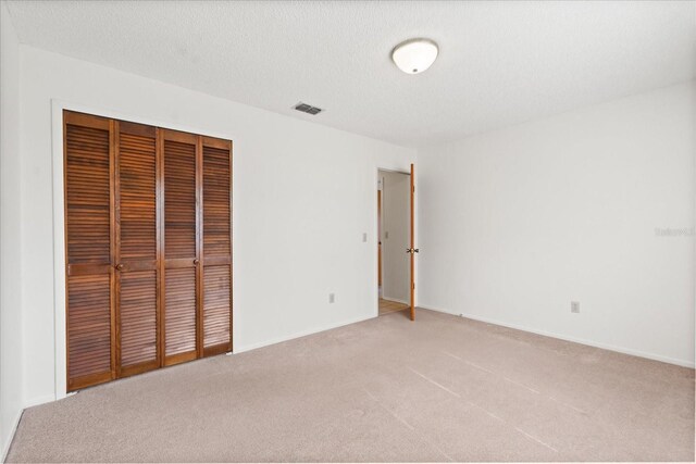 unfurnished bedroom featuring light colored carpet, baseboards, visible vents, and a closet
