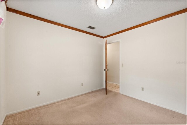 spare room with a textured ceiling, visible vents, baseboards, and light carpet